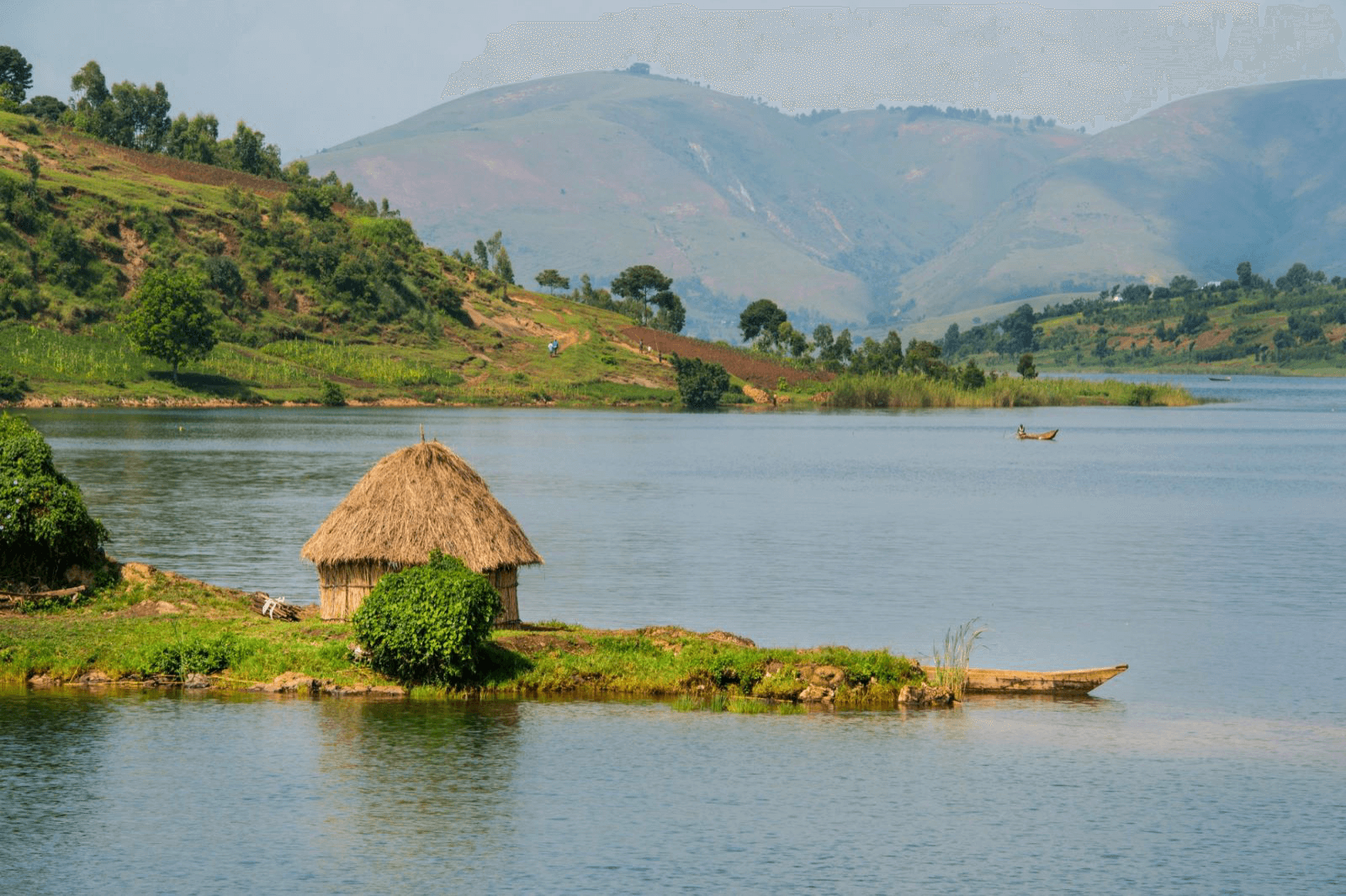 Landschaft in der Kivu-Region mit Hütte am See und Bergen im Hintergrund