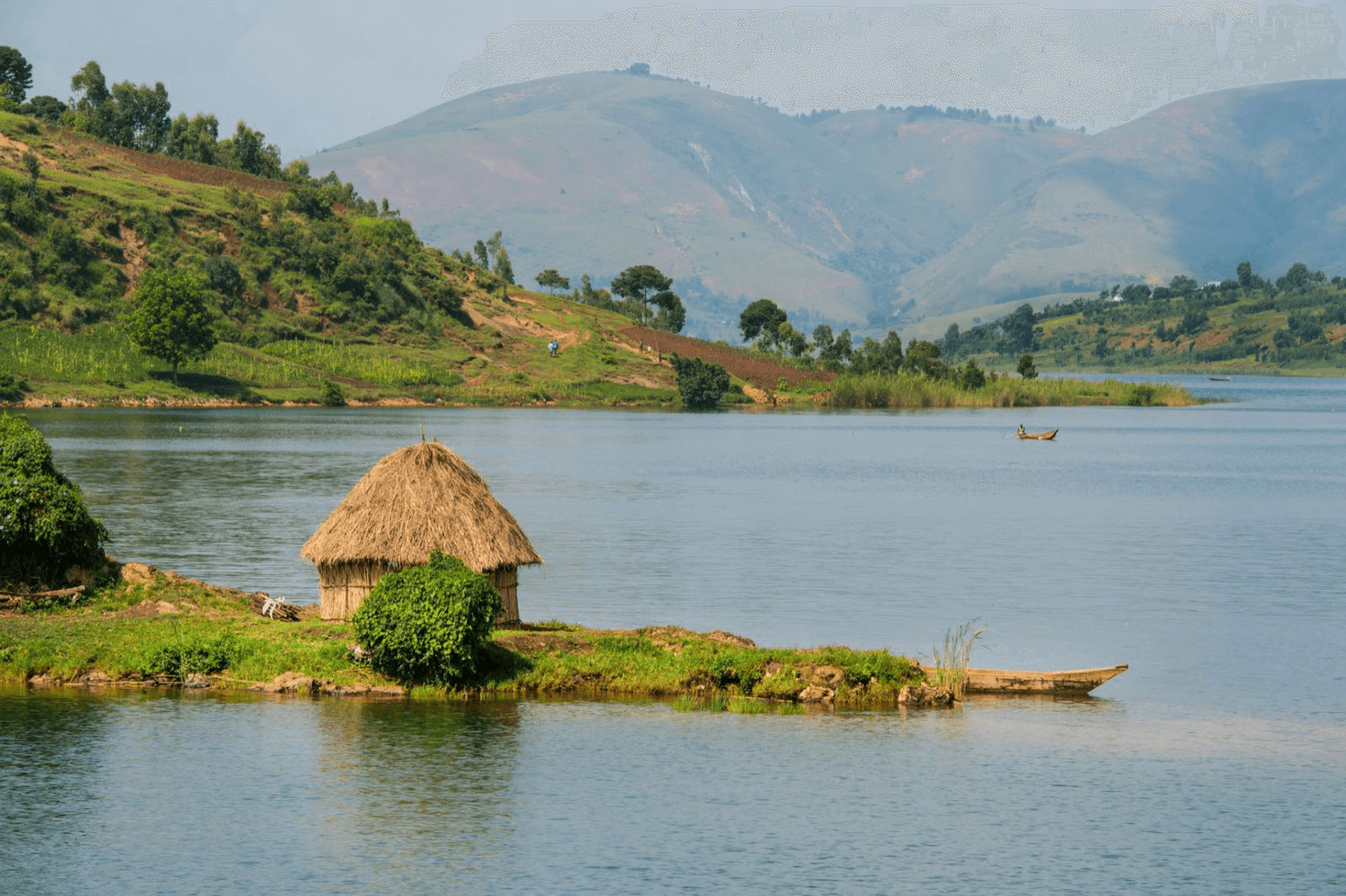 Landschaft in der Kivu-Region mit Hütte am See und Bergen im Hintergrund